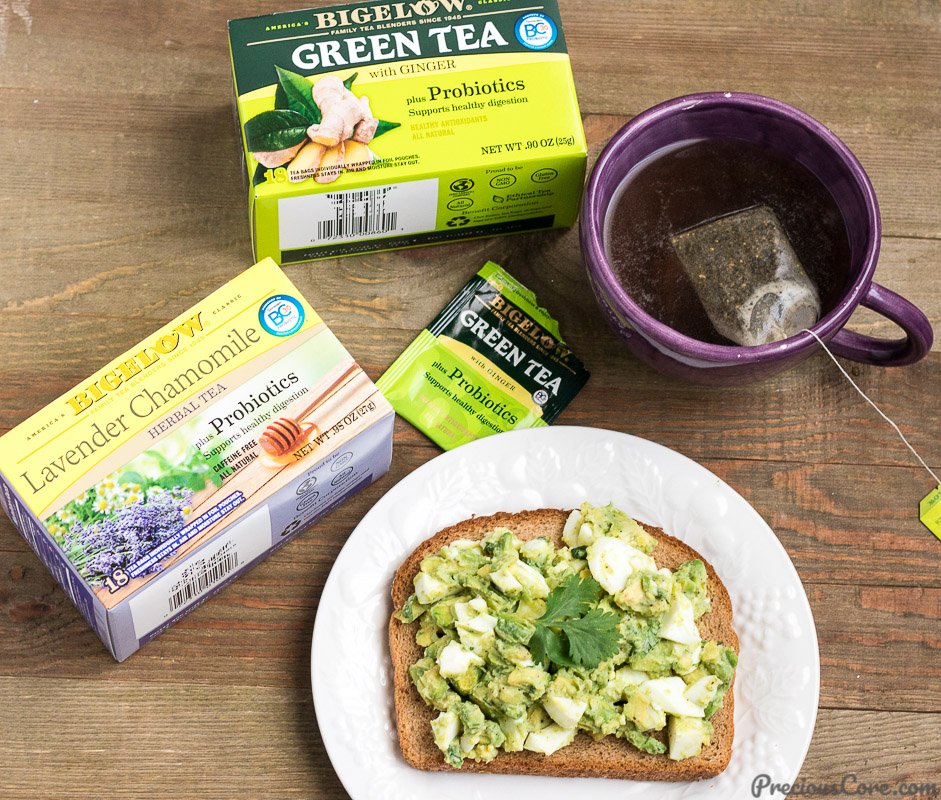 Avocado egg salad on a slice of toast on a table with tea.