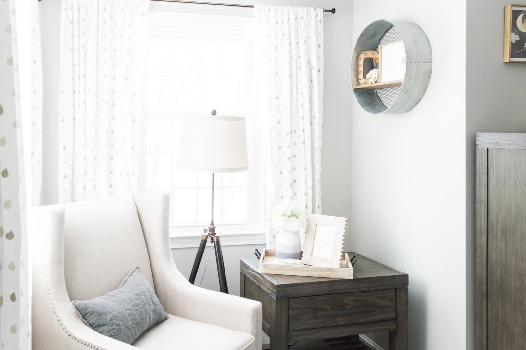 Cozy white chair, lamp and rustic end table set in baby nursery 
