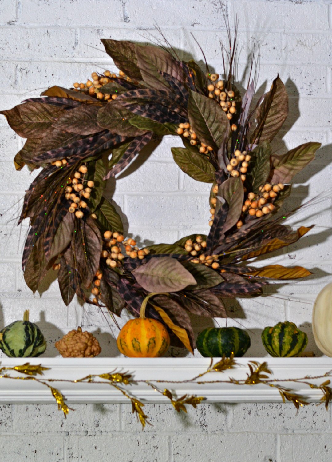 fall leaf wreath on a white mantle with white pumpkins and small pumpkins