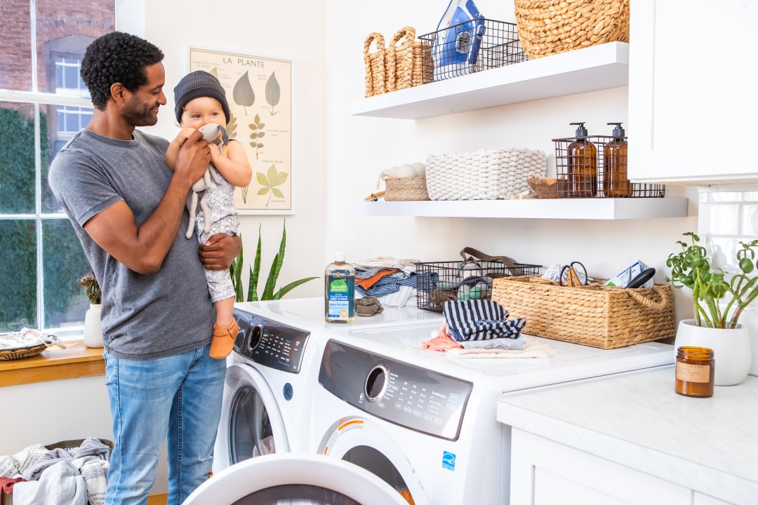 dad and toddler putting clothes into the dryer together