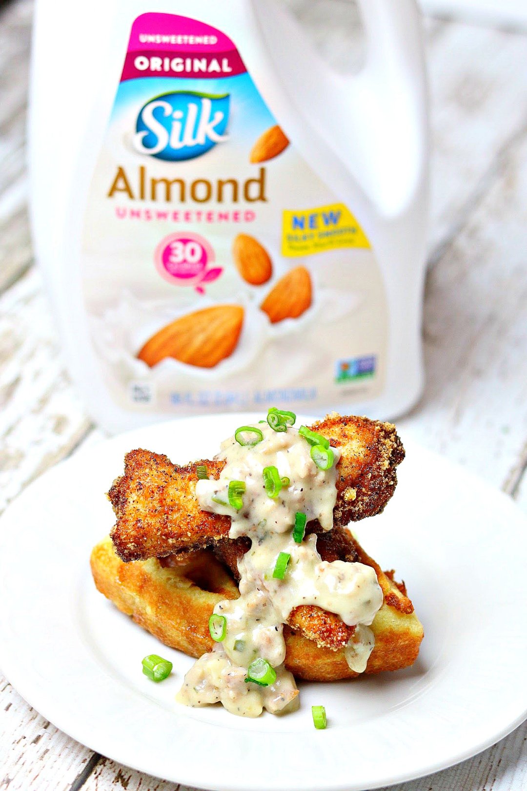 Dairy-free, Gluten-free Chicken & Waffles on a white plate with a container of Silk Almond Milk behind it.