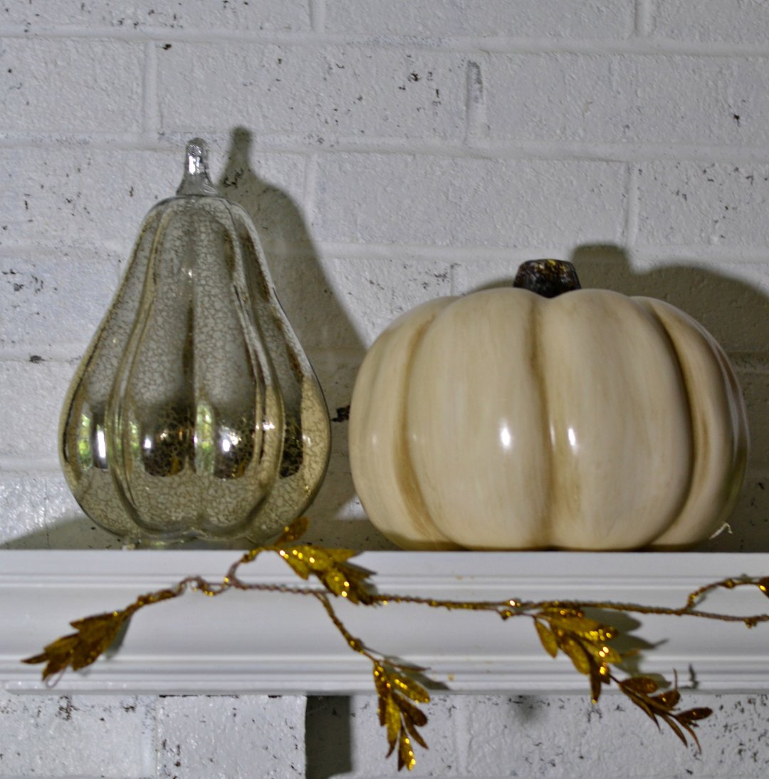 closeup of two glass pumpkins on a white mantel
