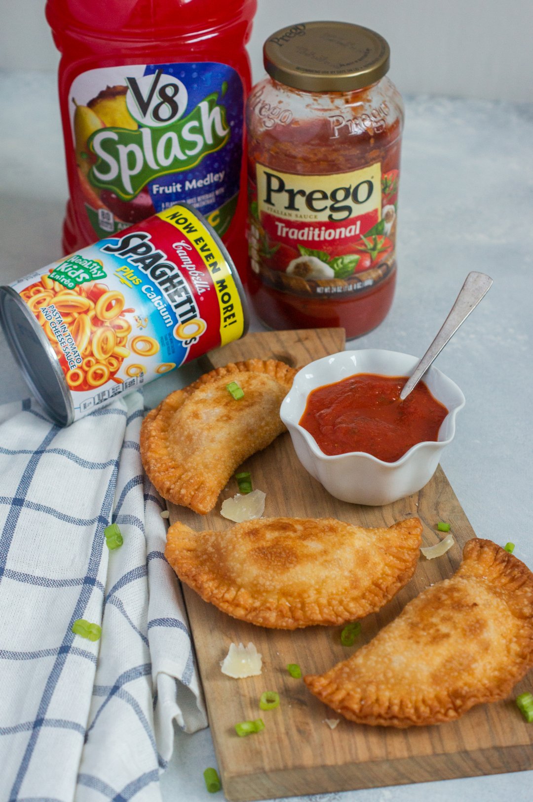 Empanadas on a board next to jars and cans of food.