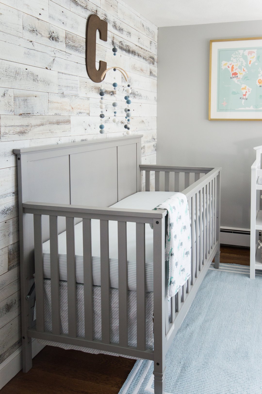 Grey crib nestled again reclaimed wood accent wall in baby boy nursery