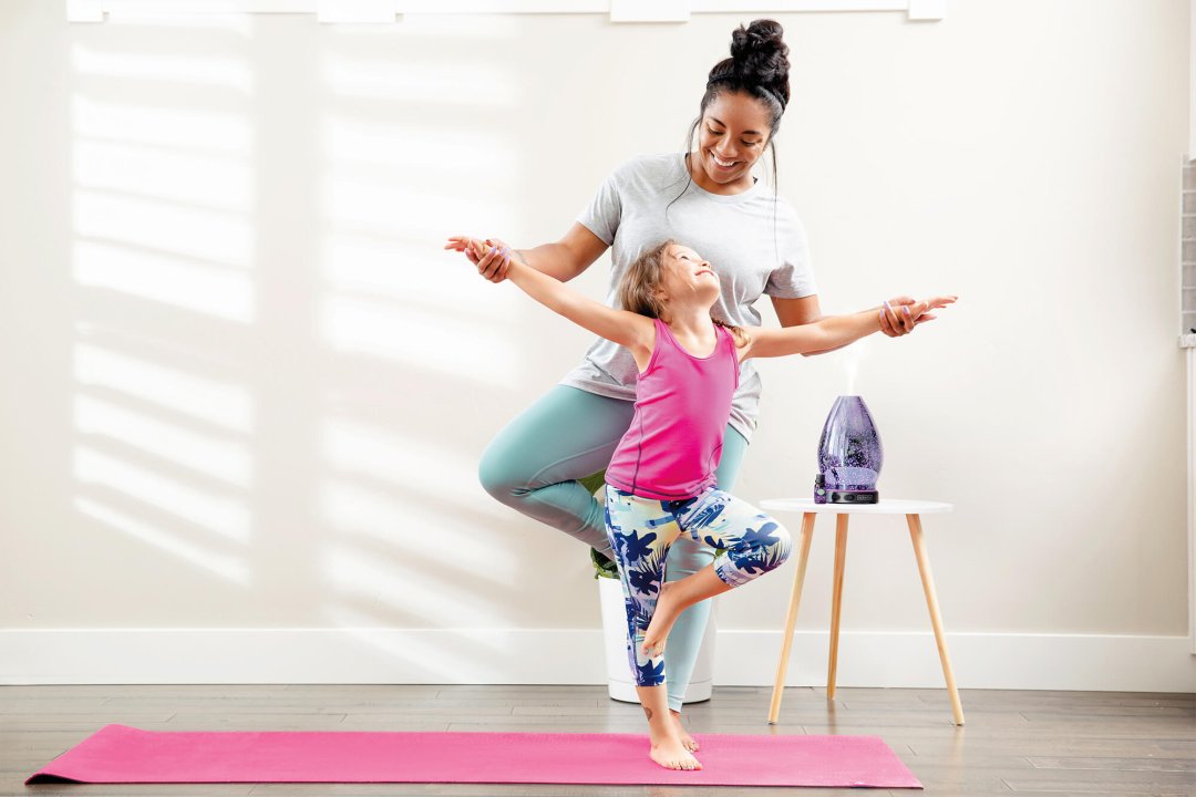 A mom and daughter doing yoga with the Scentsy Reflect diffuser expelling our cactus pear scented essential oils